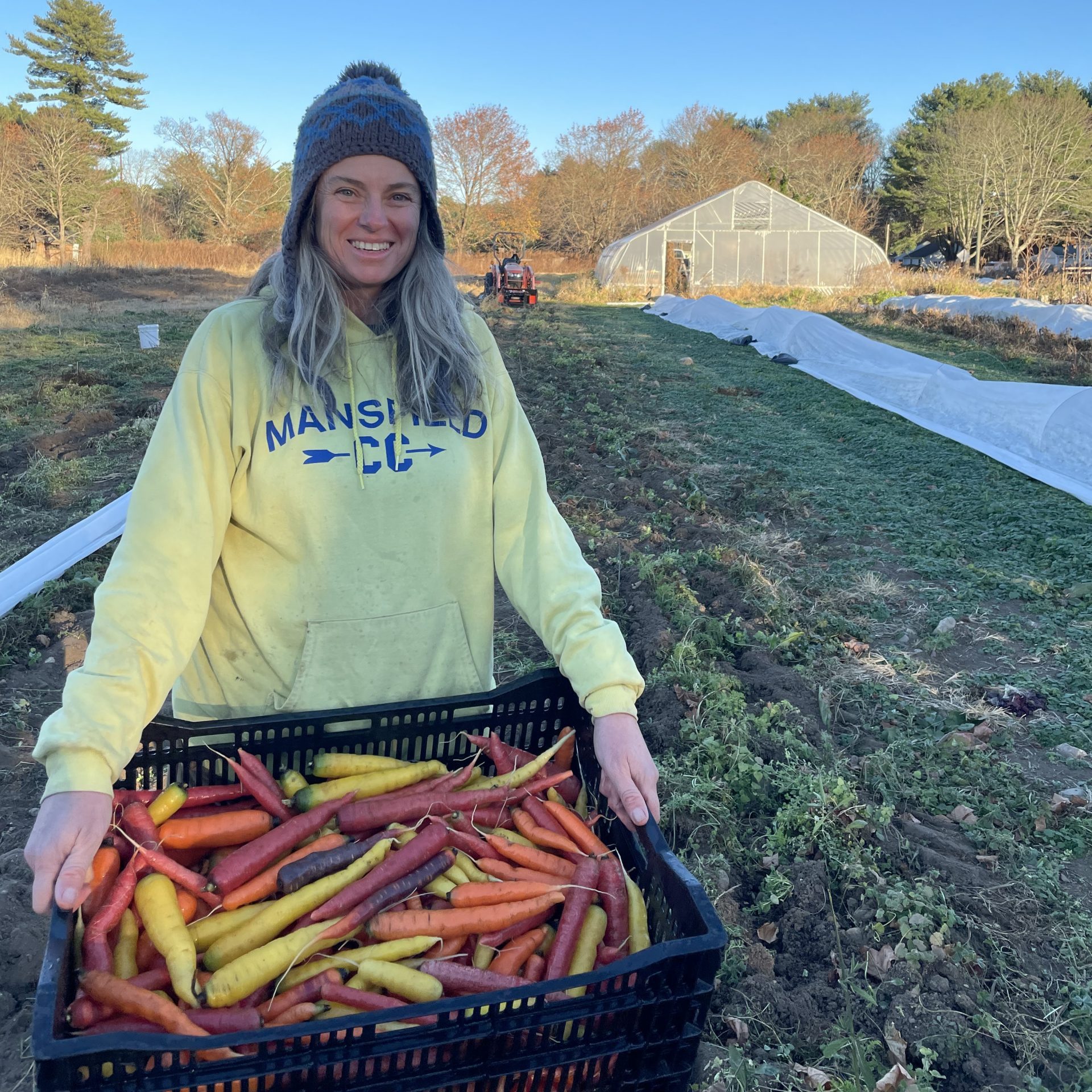 Diane Dorfer holding a crate of rainbow carrots.
