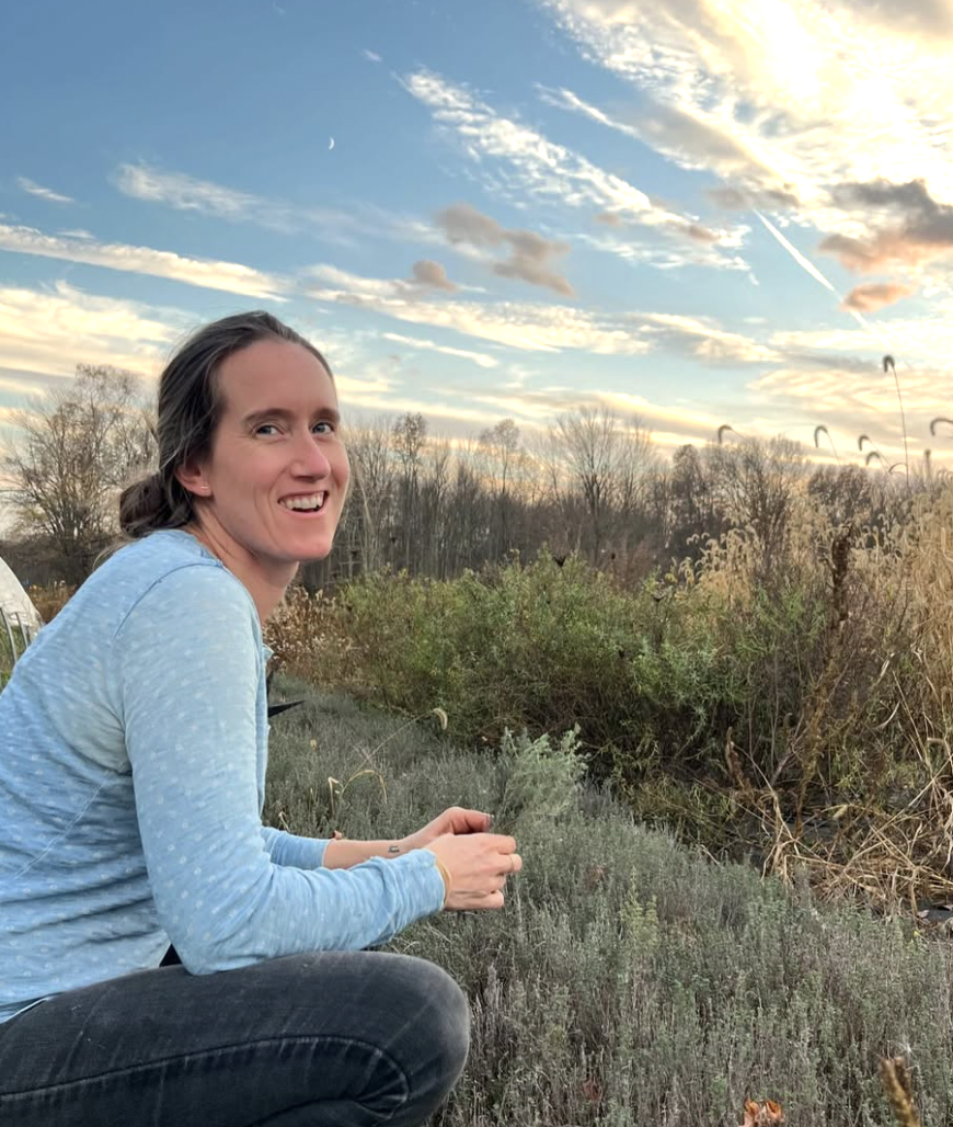 Becca Toms in a field picking herbs