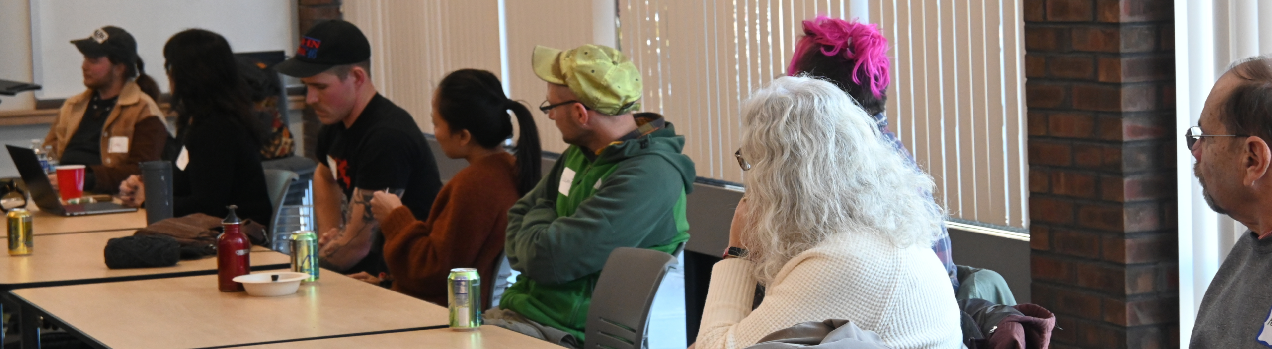 a group of farmers of different ages sitting at a table listening to a class