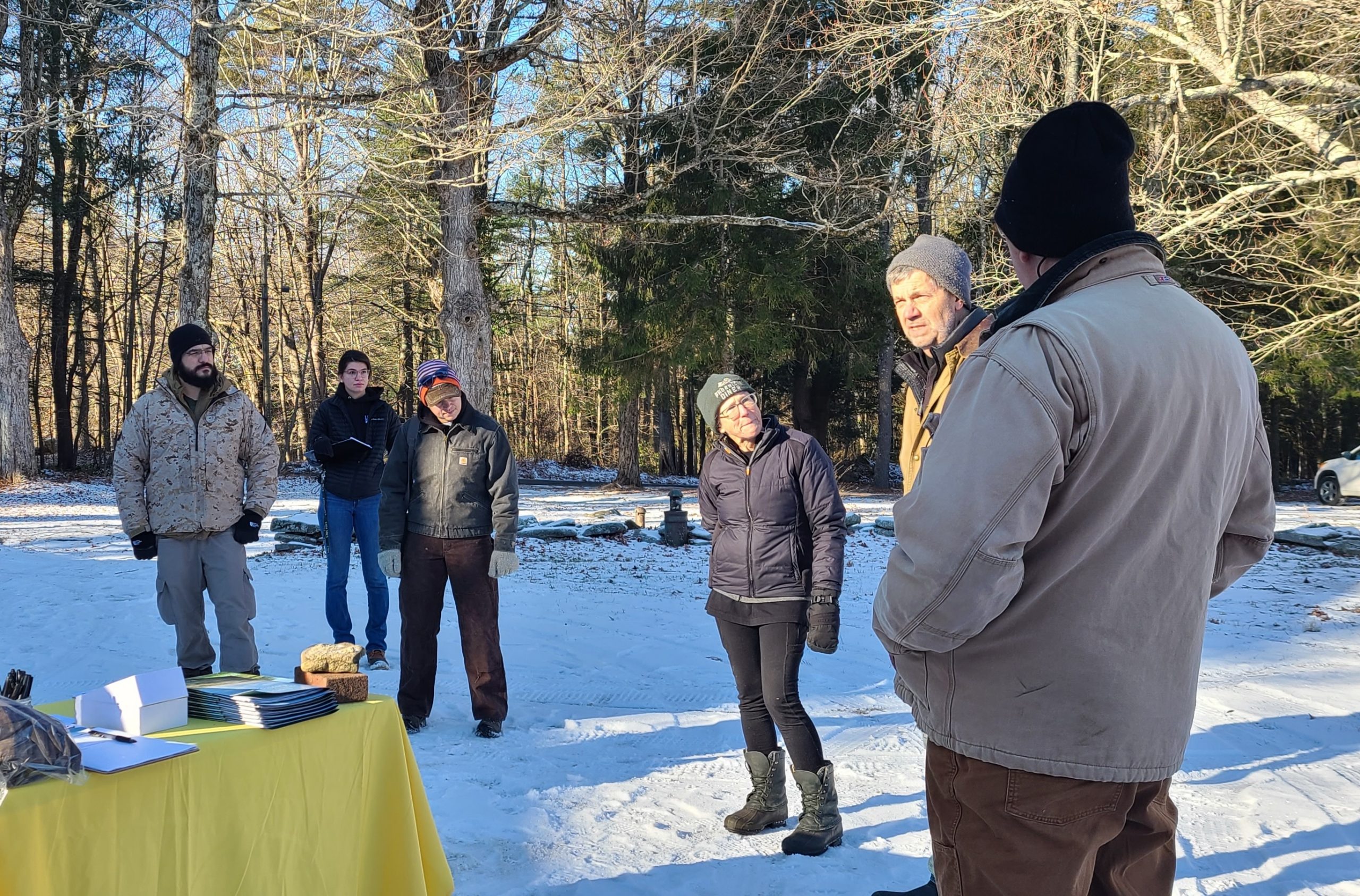 Farmers gathering around a speaker at a farm cover in snow