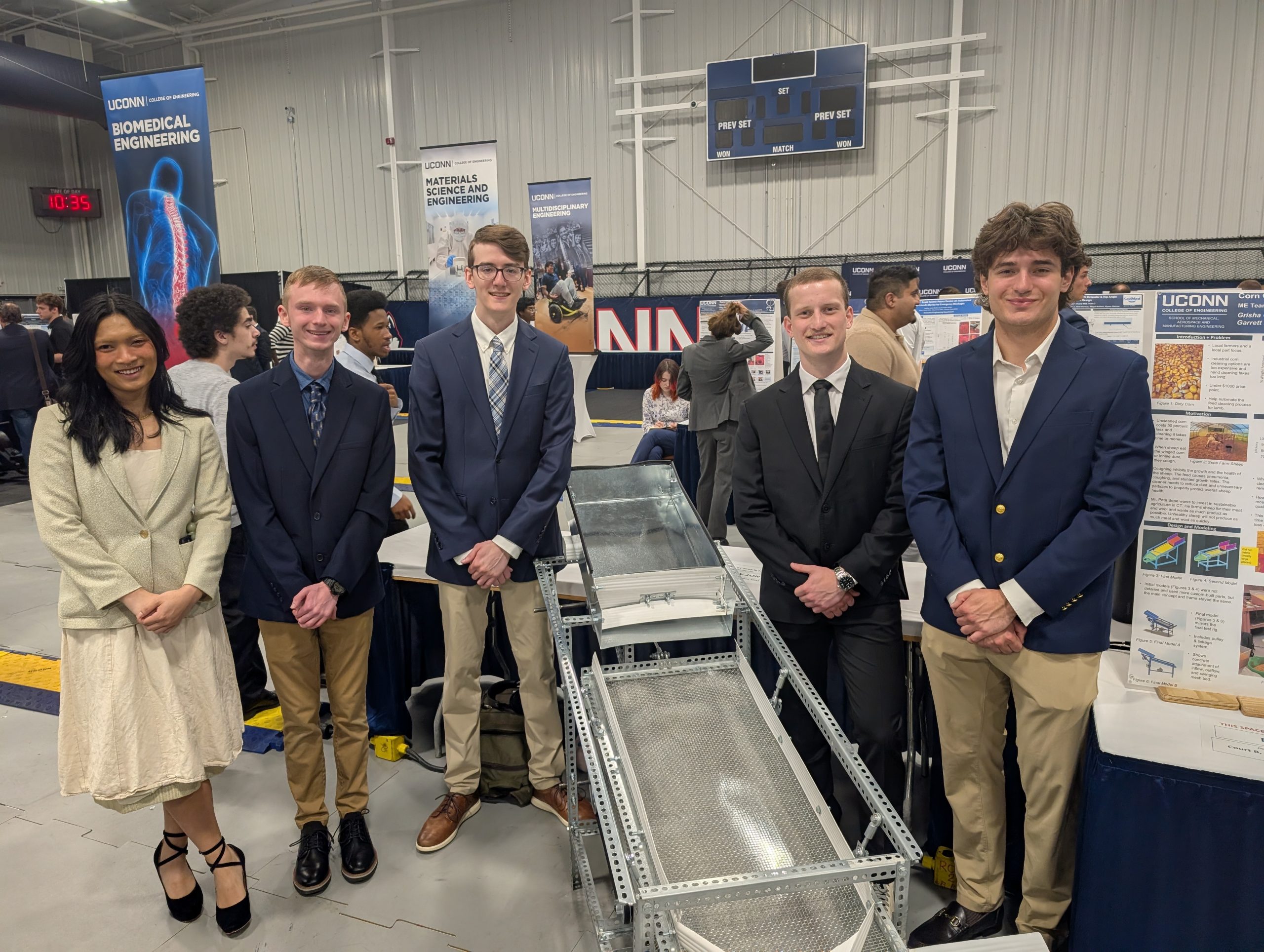 students stand around metal table for shaking corn cobs